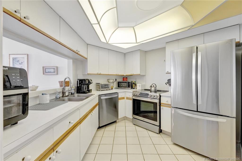 9500 South Ocean Drive, Unit HIGHER Jensen Beach, FL 34957 - Photo 14 of 53 a kitchen with a refrigerator sink and white cabinets