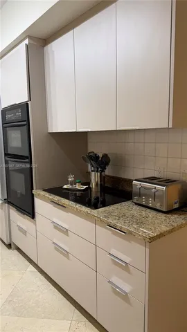 a kitchen with granite countertop white cabinets and white appliances