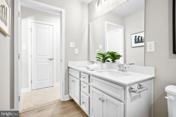 a large white kitchen with a lot of white cabinets and wooden floor