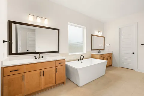 a bathroom with a double vanity sink mirror and bathtub