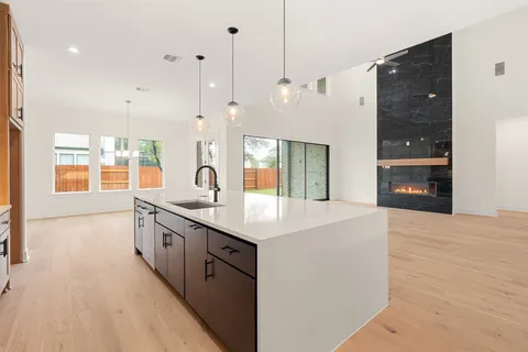 a large white kitchen with a large window a sink and stainless steel appliances
