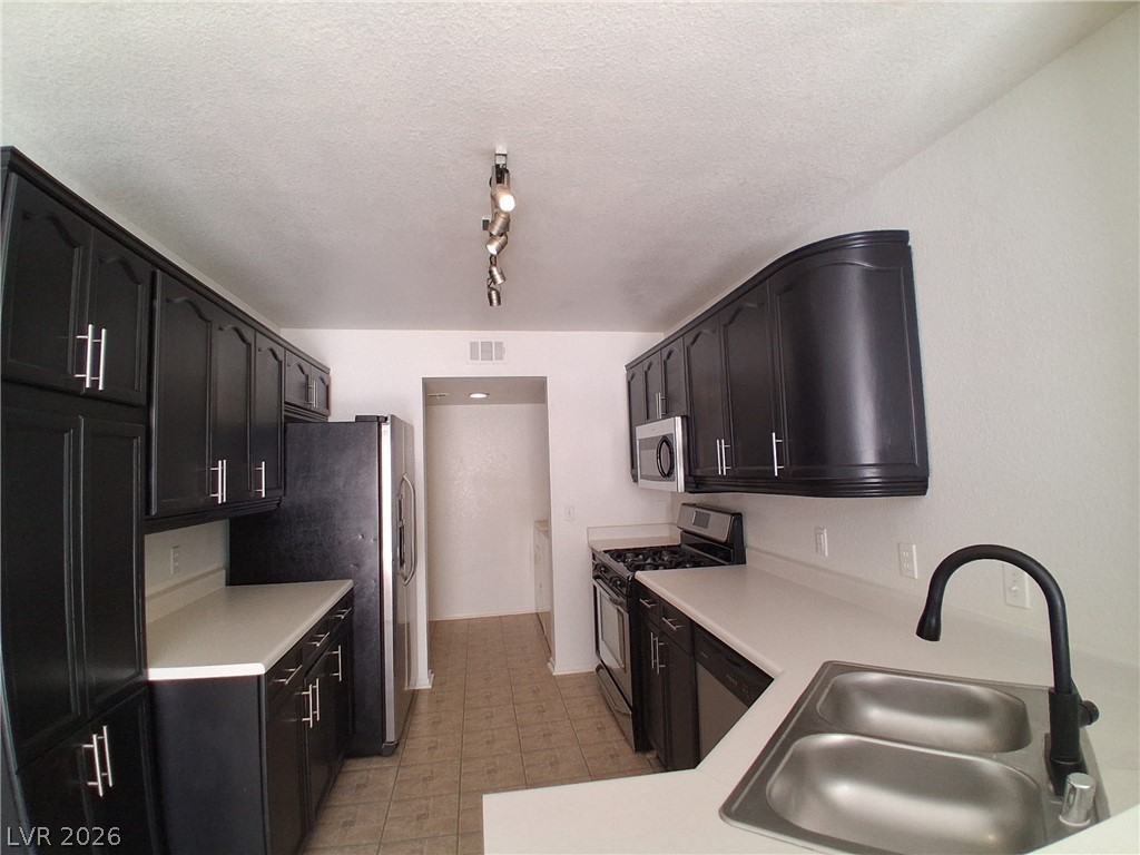 8023 Simone Avenue Las Vegas, NV 89147 - Photo 4 of 12 A well-appointed kitchen features dark cabinetry, bright countertops, and modern appliances.
