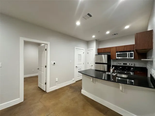 a kitchen with stainless steel appliances granite countertop a sink and a refrigerator