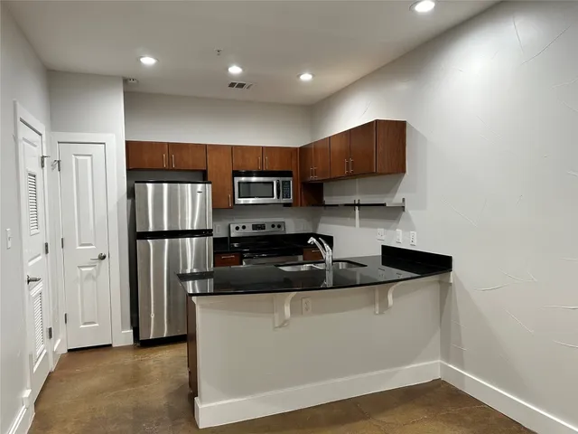 a kitchen with stainless steel appliances granite countertop a sink a stove and a refrigerator