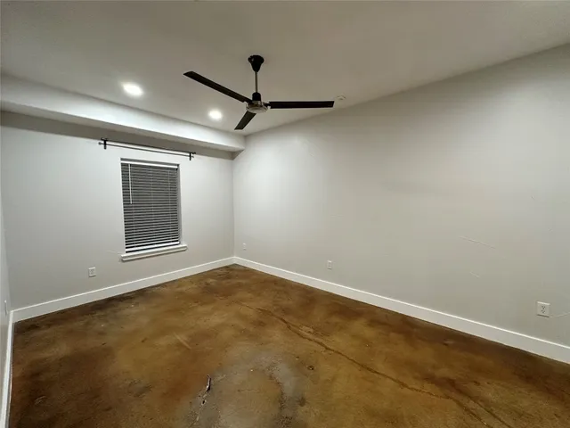 an empty room with a ceiling fan and window
