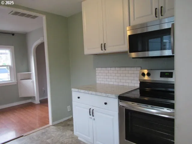 a kitchen with stainless steel appliances granite countertop white cabinets and a stove top oven