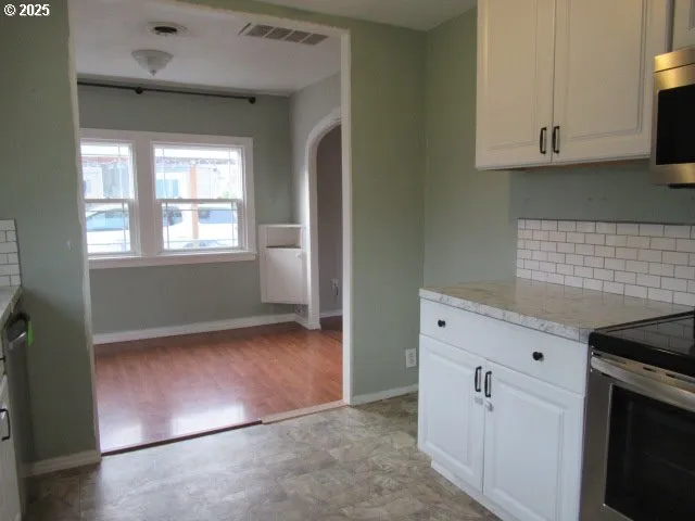 a view of kitchen with granite countertop white cabinets and white appliances