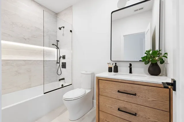 a bathroom with a sink a toilet a mirror and shower