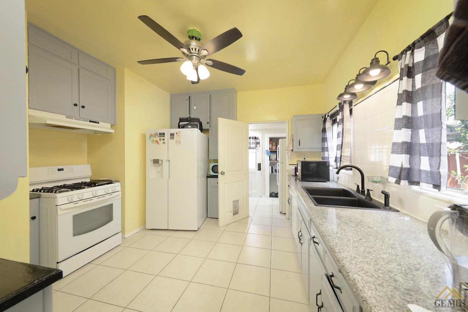 Undisclosed Address Bakersfield, CA 93305 - Photo 15 of 29 a kitchen with stainless steel appliances granite countertop a stove a refrigerator a oven with white cabinets and wooden floor