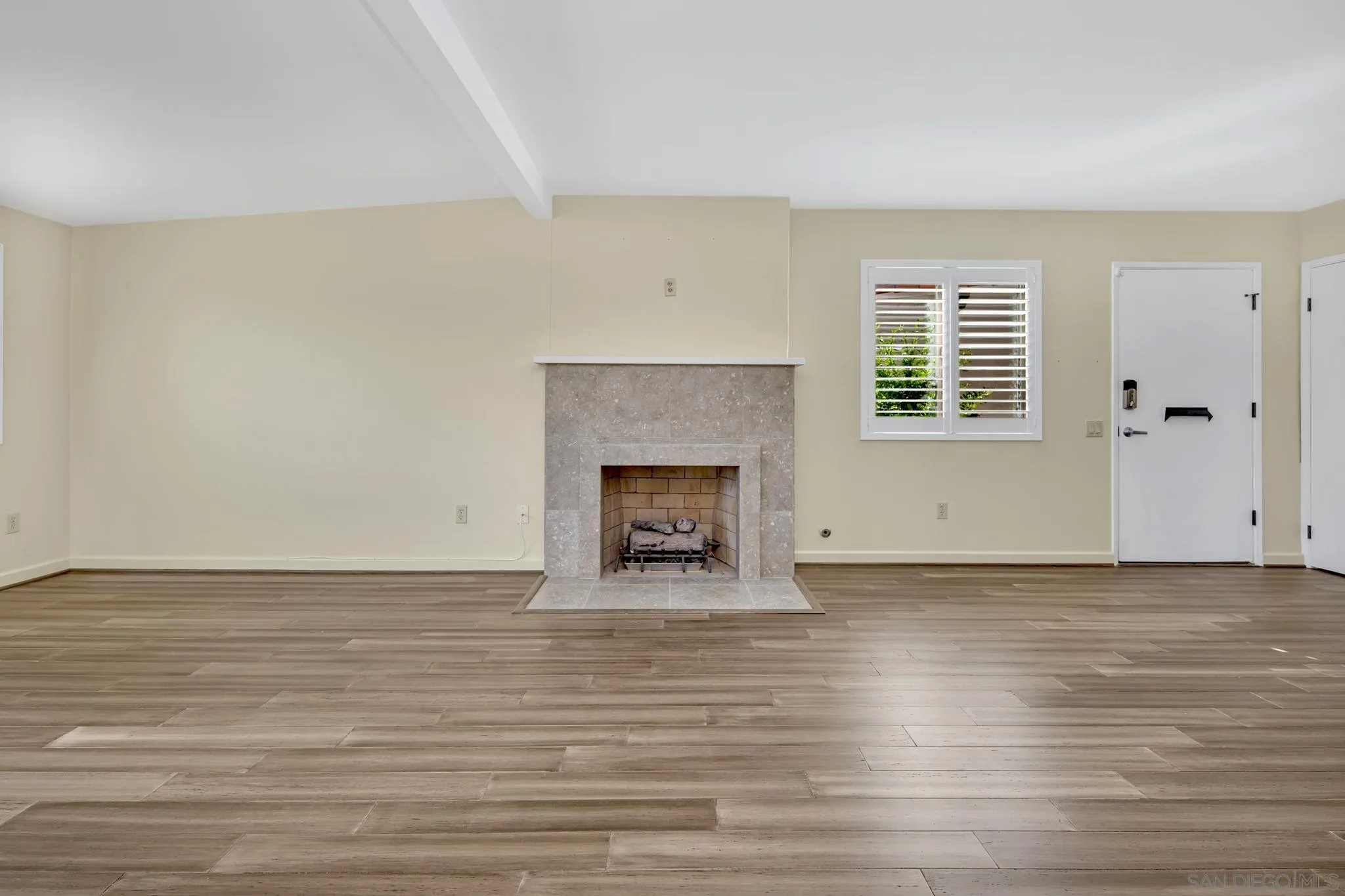 12544 Rios Road San Diego, CA 92128 - Photo 3 of 25 a view of an empty room with wooden floor fireplace and a window