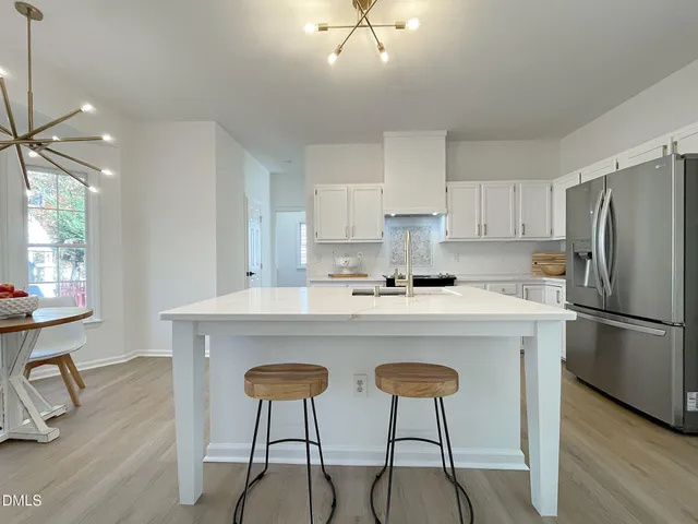 a kitchen with stainless steel appliances a table chairs refrigerator and cabinets