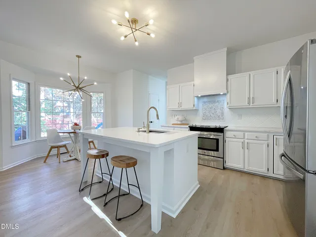 a kitchen with stainless steel appliances a table and chairs