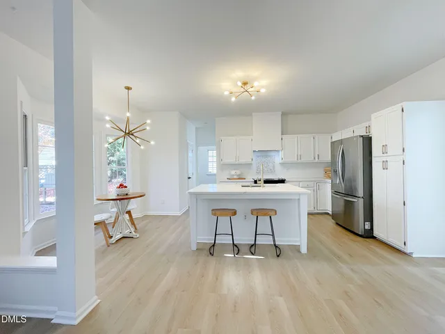 a kitchen with stainless steel appliances a dining table chairs refrigerator and sink