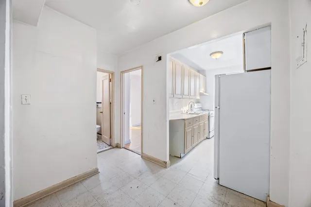 a kitchen with white cabinets and refrigerator
