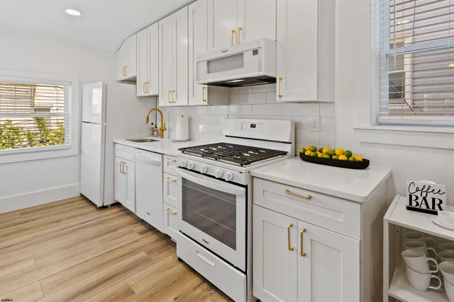 a kitchen with stainless steel appliances white cabinets a stove a sink and a window