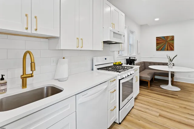 a kitchen with stainless steel appliances granite countertop a sink a stove and white cabinets with wooden floor