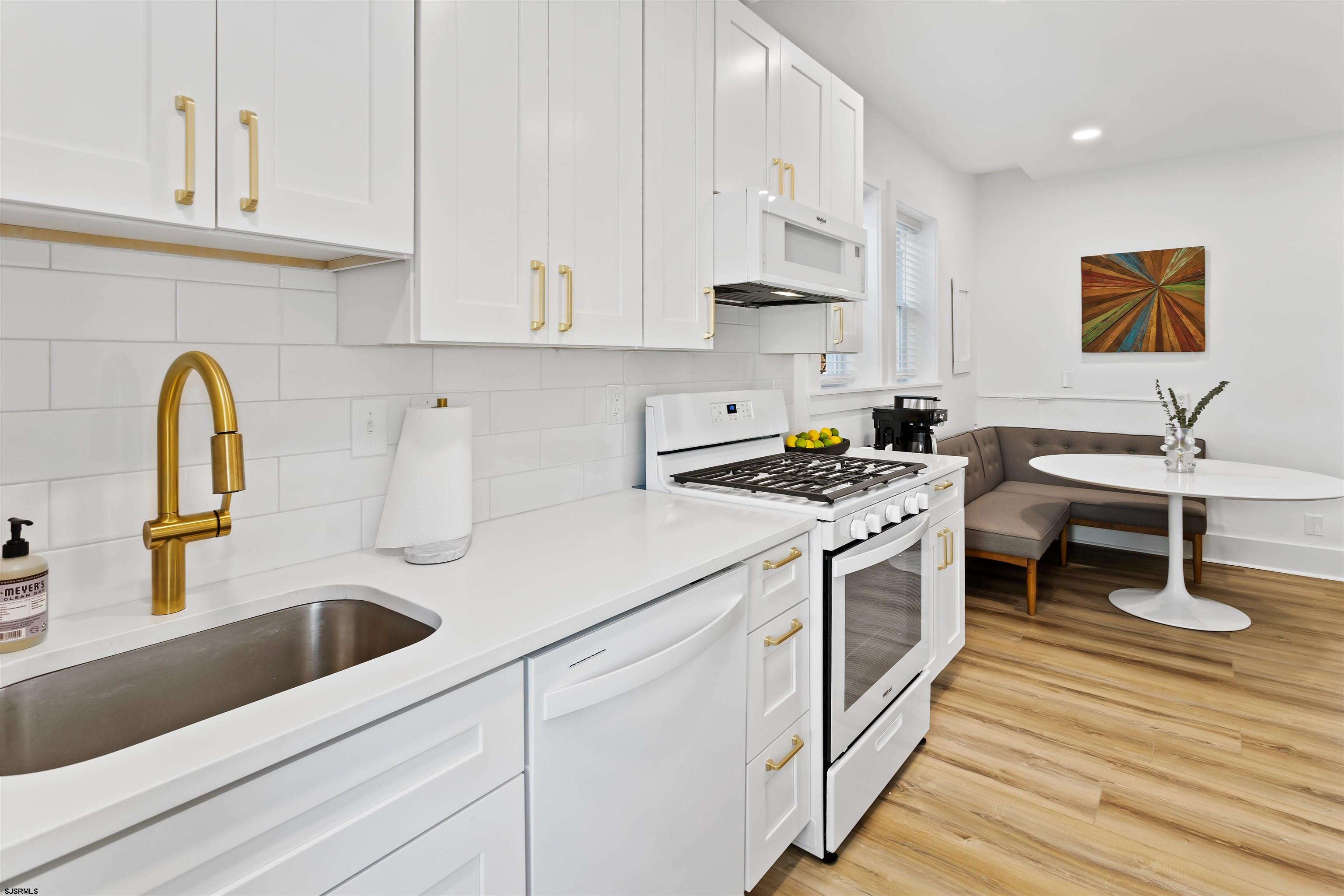 1 South Delancy Place, Unit 1 Atlantic City, NJ 08401 - Photo 33 of 35 a kitchen with stainless steel appliances granite countertop a sink a stove and white cabinets with wooden floor