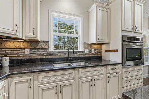 a kitchen with granite countertop white cabinets stainless steel appliances and a window