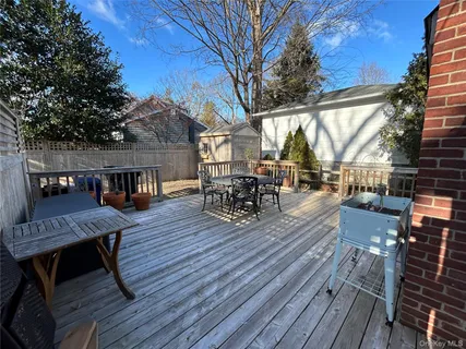 a view of a roof deck with table and chairs couches with wooden floor and fence