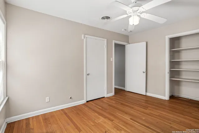 a view of an empty room with a window and wooden floor