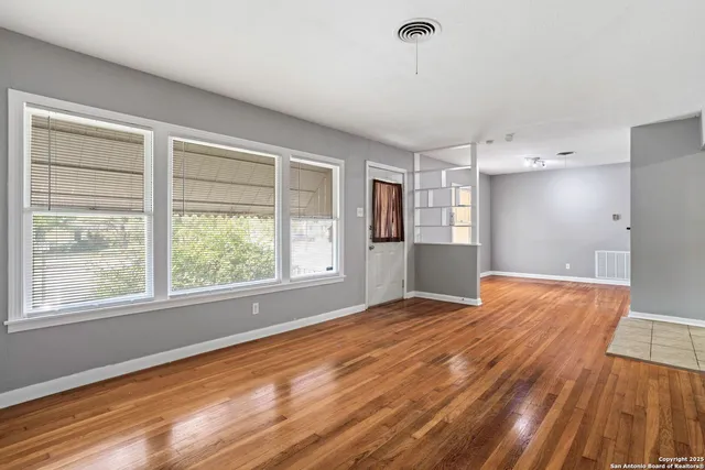 a view of an empty room with wooden floor and a window