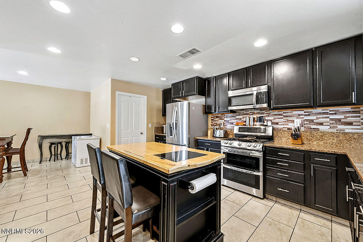 11365 Torino Way Reno, NV 89521 - Photo 14 of 29 a kitchen with stainless steel appliances kitchen island granite countertop a stove a refrigerator a sink a dining table and chairs