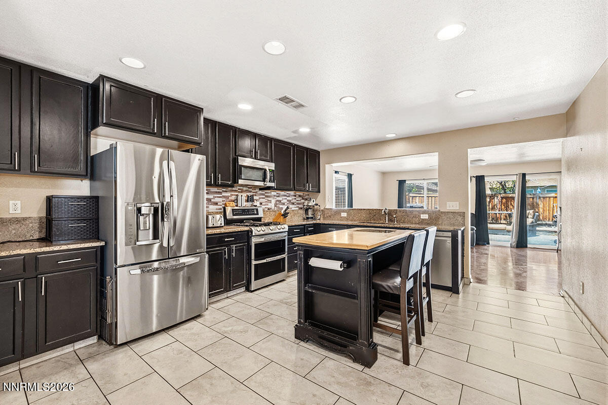 11365 Torino Way Reno, NV 89521 - Photo 16 of 29 a kitchen with stainless steel appliances granite countertop a refrigerator a stove a sink a dining table and chairs