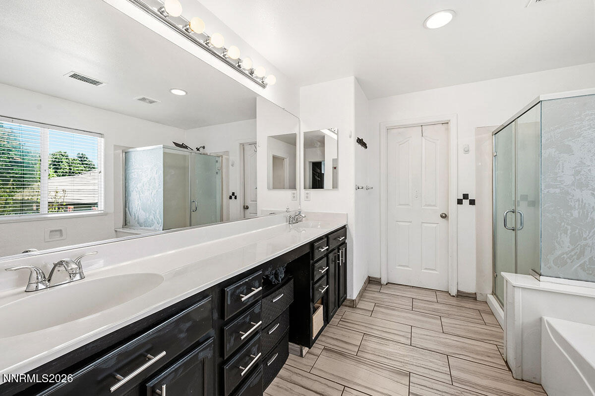 11365 Torino Way Reno, NV 89521 - Photo 25 of 29 a spacious bathroom with a double vanity sink a large mirror a shower and a bathtub