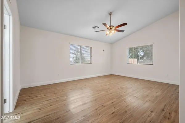 a view of an empty room with a window and wooden floor