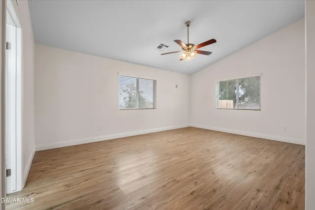 a view of an empty room with a window and wooden floor