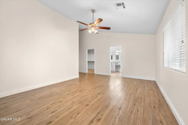 an empty room with wooden floor ceiling fan and window