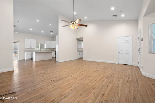an empty room with wooden floor and a kitchen