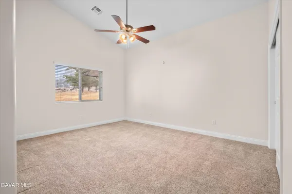 an empty room with a chandelier fan and windows