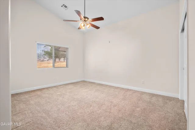 an empty room with a chandelier fan and windows