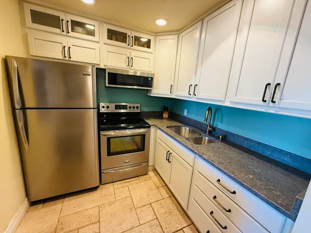 a kitchen with stainless steel appliances granite countertop a refrigerator a stove and a sink