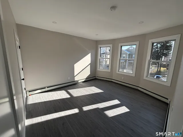 a view of an empty room with wooden floor and windows