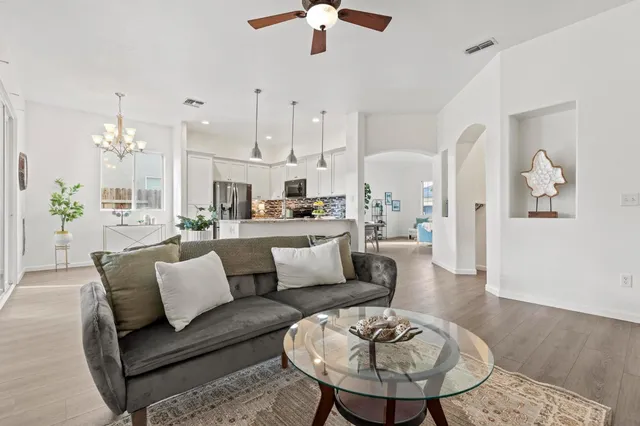 a living room with furniture kitchen view and a chandelier