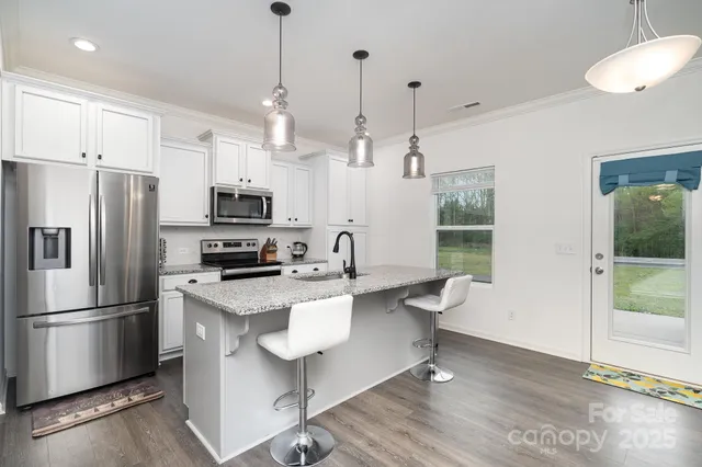 a kitchen with stainless steel appliances granite countertop a refrigerator a sink dishwasher a stove and a refrigerator with wooden floor