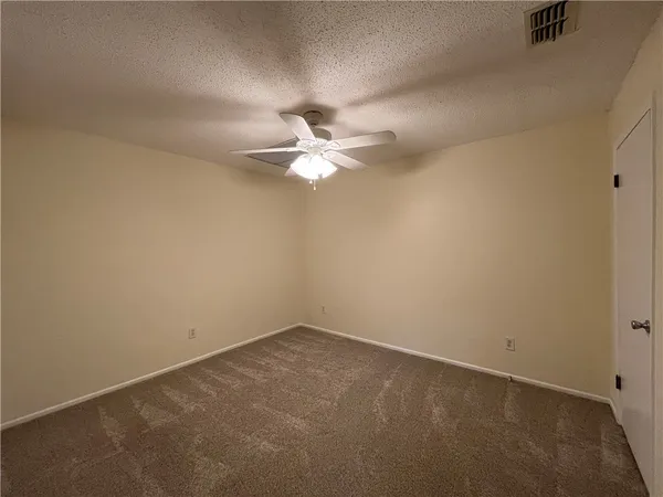 an empty room with a chandelier fan and windows