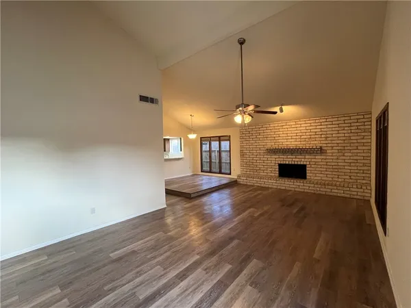 a view of a livingroom with wooden floor a ceiling fan and kitchen space