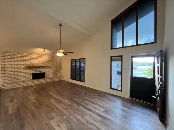 a view of a livingroom with wooden floor a fireplace and windows