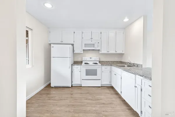 a kitchen with granite countertop white cabinets and white appliances