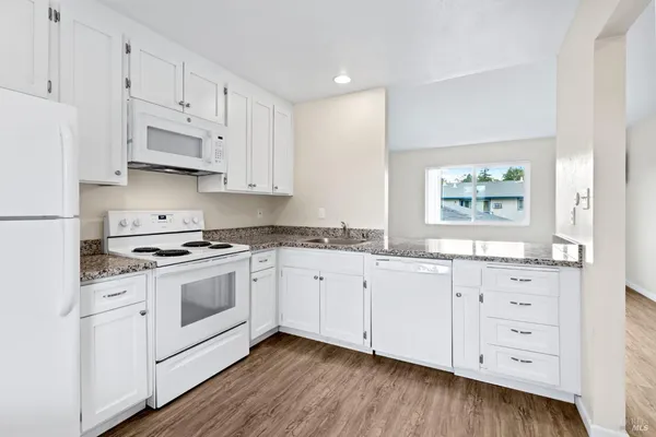 a kitchen with granite countertop white cabinets and white appliances