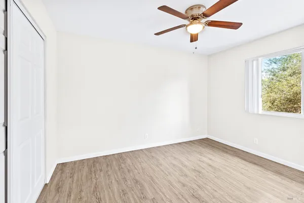 an empty room with a window and a ceiling fan