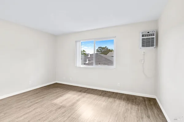 an empty room with wooden floor and window