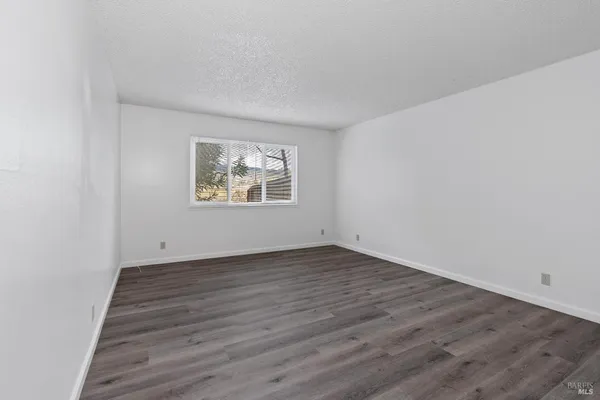 an empty room with wooden floor and window