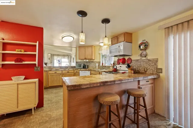 a large kitchen with kitchen island stainless steel appliances a stove center island and windows