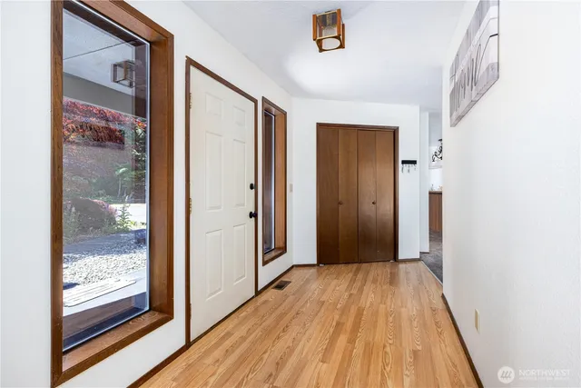 a view of a hallway with wooden floor and a bathroom