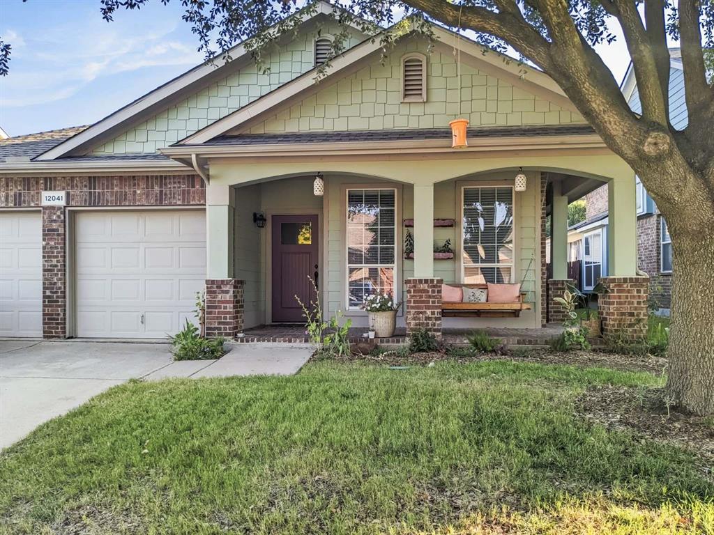 View of front facade with driveway, a porch, a garage, brick siding, and a front yard
