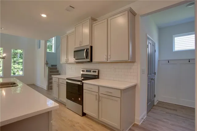 a kitchen with stainless steel appliances granite countertop a sink a stove and a wooden floors